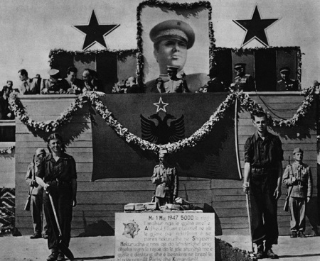Discurso de Hoxha en Tirana. En la foto se ven las estrellas que hacen alusión al comunismo y la bandera de la Albania comunista (con la estrella sobre las águilas).